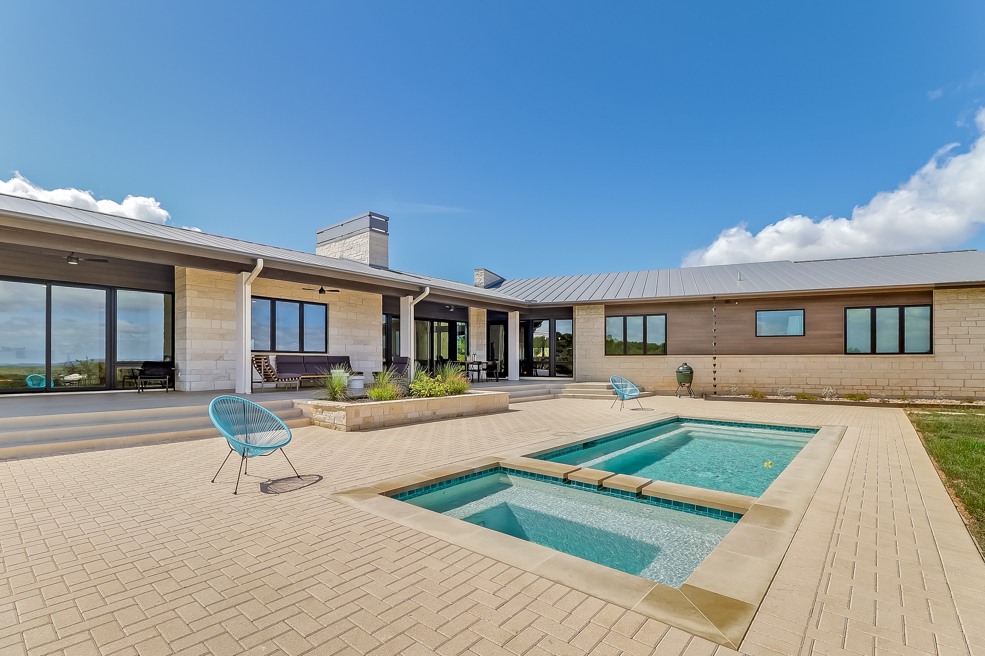 Wide pool and courtyard with stone exterior and metal roof, The Architect's View
