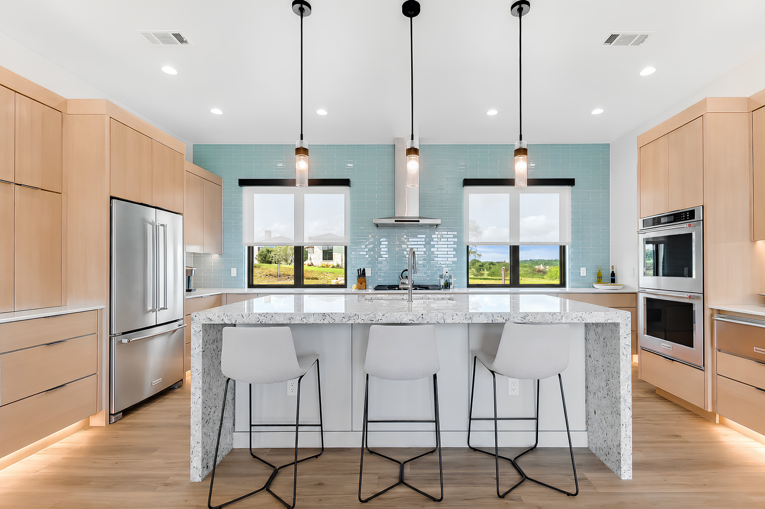 Kitchen with terrazzo island, turquoise tile backsplash, and light wood cabinetry, The Architect's View